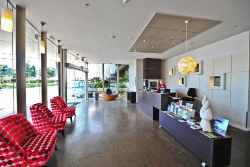 a lobby with red chairs and a counter at Millennium Hotel New Plymouth, Waterfront in New Plymouth