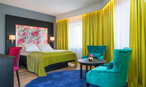 um quarto de hotel com uma cama e cadeiras coloridas em Thon Hotel Arendal em Arendal