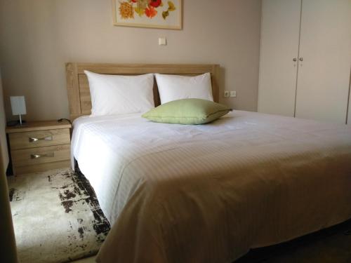 a bedroom with a large white bed with a green pillow at Theanthi in Nafplio