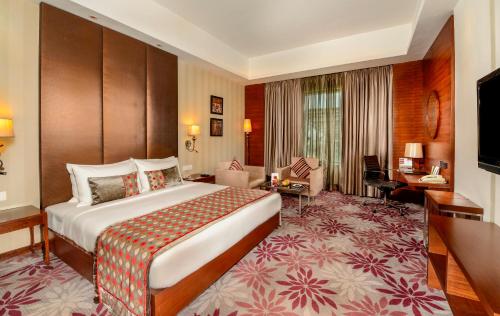 a hotel room with a large bed and a desk at Pride Plaza Hotel, Kolkata in Kolkata