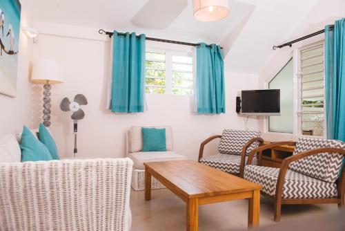 a living room with blue curtains and a table and chairs at Coconuts in Grand Baie