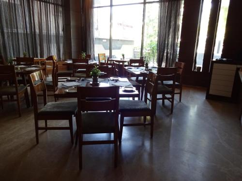 a dining room with tables and chairs and a large window at Hotel Cosmopolitan in Ahmedabad