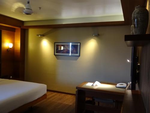 a room with a bed and a picture on the wall at Hotel Cosmopolitan in Ahmedabad