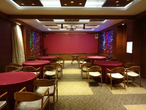 a conference room with red tables and chairs at Hotel Cosmopolitan in Ahmedabad