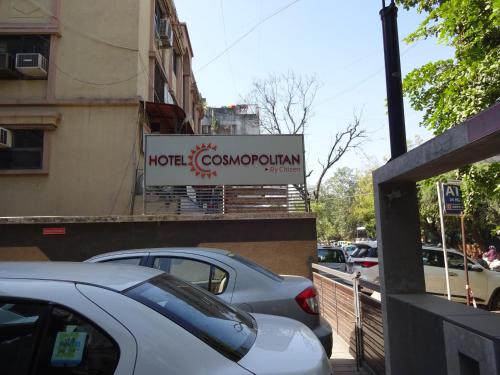a sign on the side of a building with cars parked at Hotel Cosmopolitan in Ahmedabad