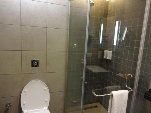 a bathroom with a shower with a toilet and a glass door at Hotel Cosmopolitan in Ahmedabad