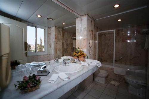uma casa de banho com um lavatório, um WC e um espelho. em Addar Hotel em Jerusalém