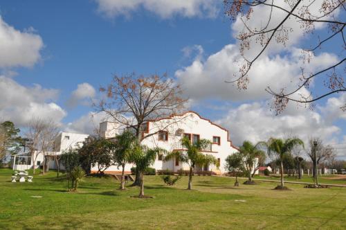 a white house with trees in a park at Hotel La Posta del Dayman in Termas del Daymán