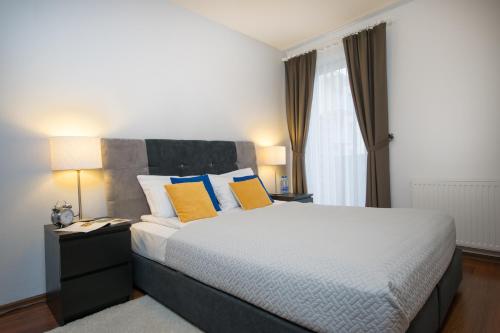 a bedroom with a bed with yellow and blue pillows at Apartament Darłówko in Darłówko