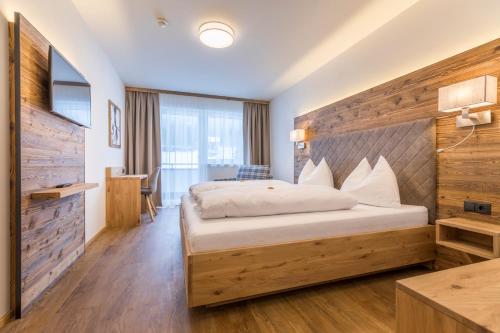 1 dormitorio con 1 cama grande y pared de madera en OFENTÜRL alpine living en Flachau