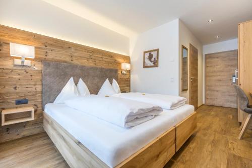 a bedroom with a large white bed with a wooden wall at OFENTÜRL alpine living in Flachau