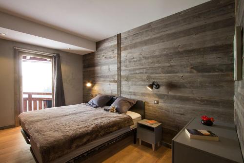a bedroom with a bed and a wooden wall at Odalys Chalet Nuance de blanc in L'Alpe-d'Huez