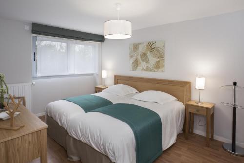 Schlafzimmer mit einem großen Bett mit weißer und grüner Bettwäsche in der Unterkunft Résidence Séniors Domitys "Les Portes de l'Atlantique" in Saint-Nazaire