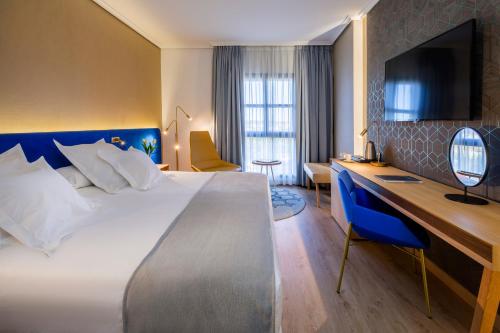 una camera d'albergo con un grande letto e una scrivania di Barceló Cáceres V Centenario a Cáceres