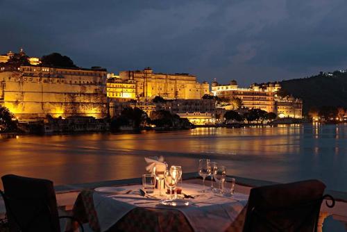 a table with wine glasses and a view of the water at Amet Haveli - A Heritage Hotel Udaipur in Udaipur