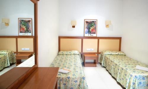 una camera con due letti e uno specchio di Apartamentos Royal a Lloret de Mar