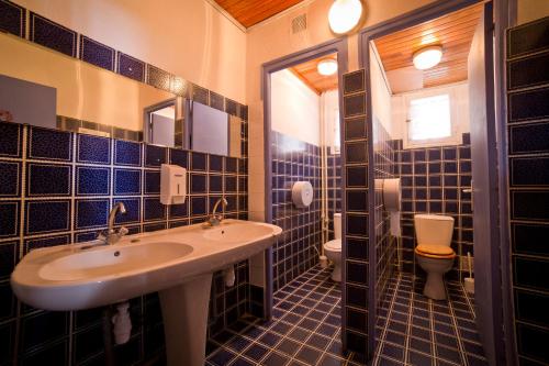 La salle de bains est pourvue de carrelage bleu, d'un lavabo et de toilettes. dans l'établissement Centre de Vacances Le Val d'Escreins, à Vars