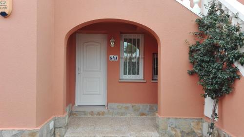 an entrance to a pink building with a white door at Apartamento entero 3 Habitaciones CLUB SEVILLA III in Casas Devesa