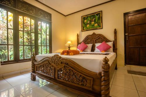 a bedroom with a large wooden bed with red pillows at Gusti Kaler House in Ubud