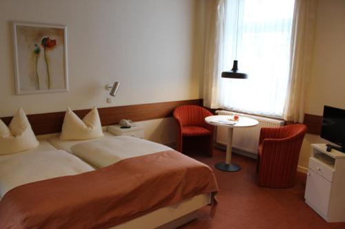 a hotel room with a bed and a table and chairs at Hotel Sonnenklause in Travemünde