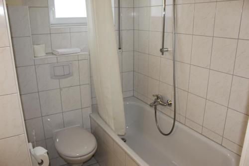 a bathroom with a shower and a toilet and a tub at Hotel Sonnenklause in Travemünde