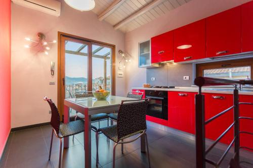 a kitchen with red cabinets and a table with chairs at Case Spazioscena - Euterpe in Castelbuono