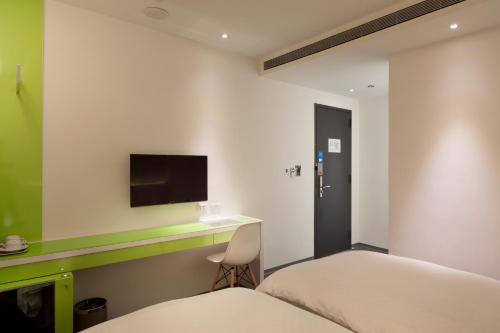 a bedroom with a bed and a desk and a tv at CityInn Hotel Plus - Taichung Station Branch in Taichung