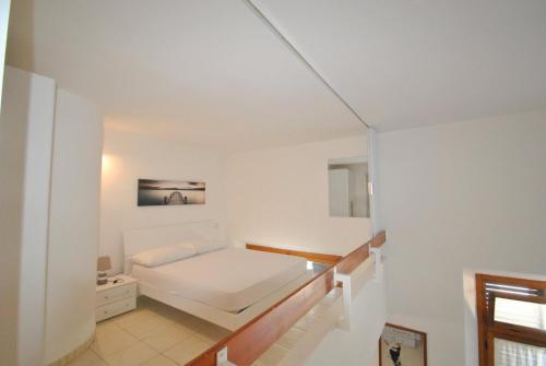 1 dormitorio blanco con 1 cama y escalera en La Perla, en Castiglioncello