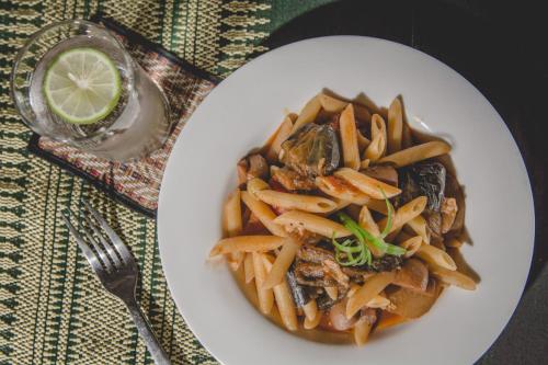 a plate of pasta with mushrooms and a slice of lime at Terres Rouges Lodge in Banlung