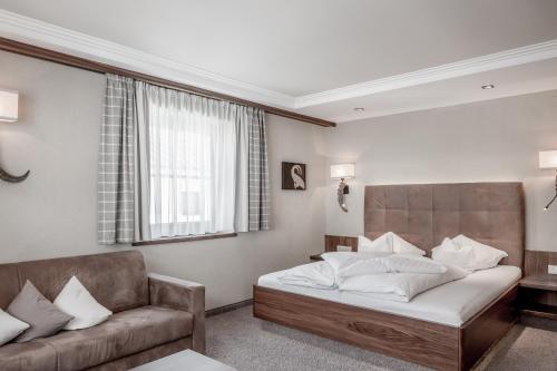 a bedroom with a bed and a couch and a window at Hotel Garni Caroline in Ischgl