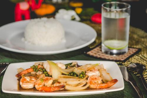 a plate of shrimp with rice and a glass of water at Terres Rouges Lodge in Banlung