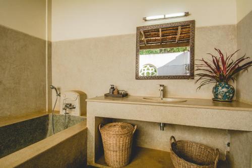 a bathroom with a sink and a tub and a mirror at Terres Rouges Lodge in Banlung