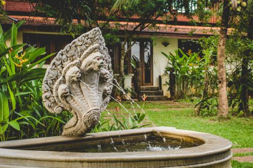 a statue of a fountain in front of a house at Terres Rouges Lodge in Banlung