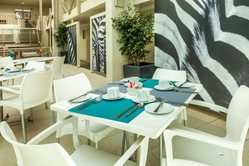 a dining room with white tables and white chairs at Peermont Metcourt Hotel in Francistown