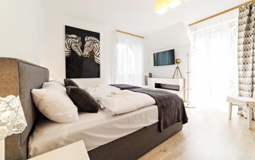a bedroom with a bed with white sheets and pillows at Apartamenty Sun & Snow na Wilczej in Karpacz