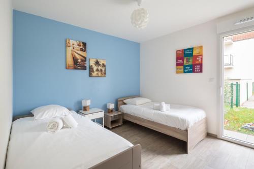 - 2 lits dans une chambre aux murs bleus dans l'établissement Le Garden by Cocoonr, à Dinard