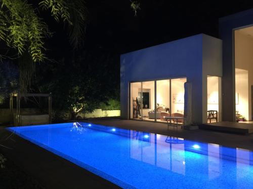 a swimming pool in front of a house at night at Villa Alice Caesarea in Caesarea