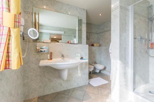 a bathroom with a sink and a shower at Lohmann's Romantik Hotel Gravenberg in Langenfeld