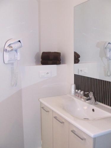 a white bathroom with a sink and a mirror at Hôtel Patton in Avranches