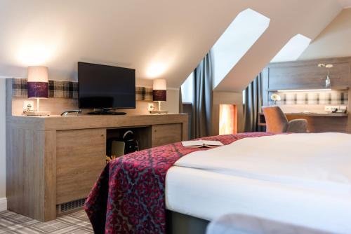 a hotel room with a bed and a flat screen tv at Lohmann's Romantik Hotel Gravenberg in Langenfeld