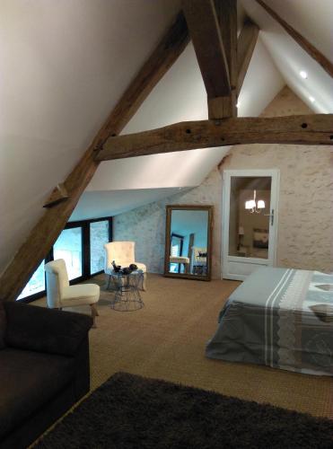 Cette chambre mansardée comprend un lit, une table et des chaises. dans l'établissement Ode au Bonheur St Georges sur Cher, à Saint-Georges-sur-Cher