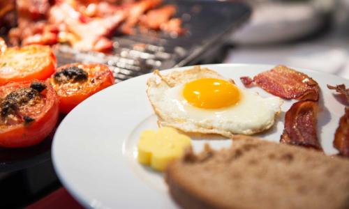 un plato de desayuno con huevo y tocino en Thon Hotel Lillestrøm en Lillestrøm