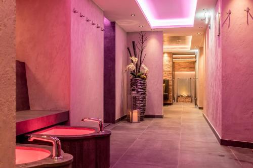 a pink bathroom with two sinks and a vase of flowers at Hotel Garni Caroline in Ischgl