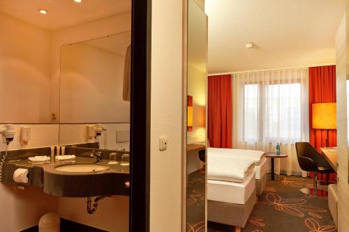 a hotel room with a bed and a sink and a mirror at H+ Hotel Hannover in Hannover