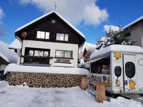 une maison enneigée avec un camion de nourriture devant elle dans l'établissement Ubytování Maxa, à Špičák