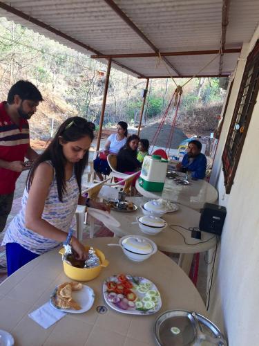 a woman standing at a table with plates of food at Jamrung Hillside Camping in Jambrung 