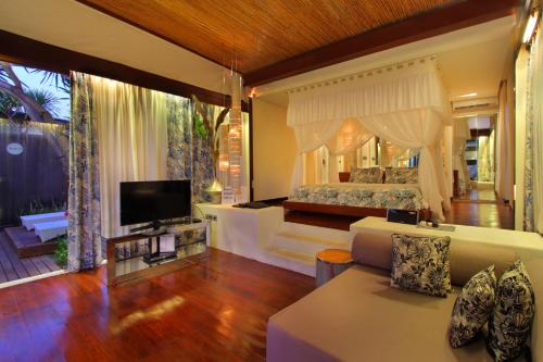- un salon avec un lit et une télévision dans l'établissement Kiss Bali Villas, à Seminyak