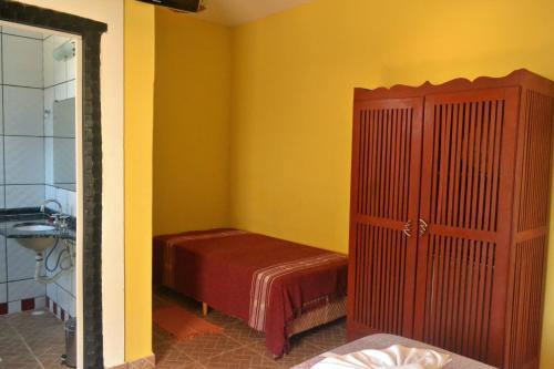 a small room with a bed and a bathroom at Pousada Casa de Pedra in Boicucanga