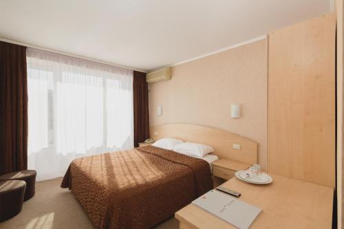 a hotel room with a bed and a desk and a window at Отель Магнолия in Sochi