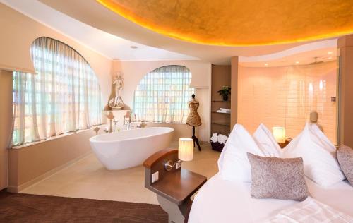 a bathroom with a tub and a bed and a bath tub at Bergergut Geniesserhotel in Afiesl